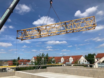 schwebende Kranteile über der Baustelle